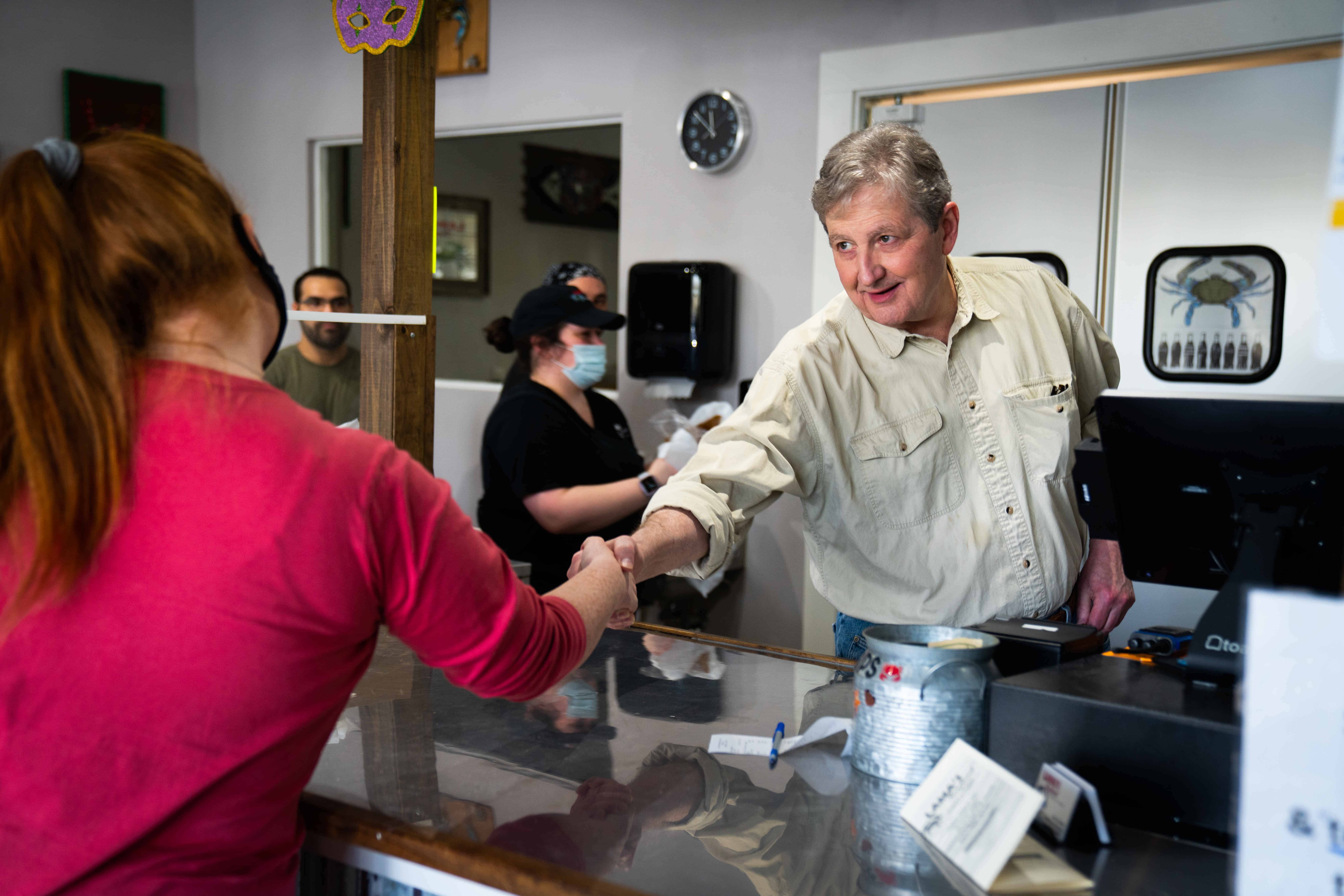 John Kennedy shaking hands with a supporter at a healthcare center event.