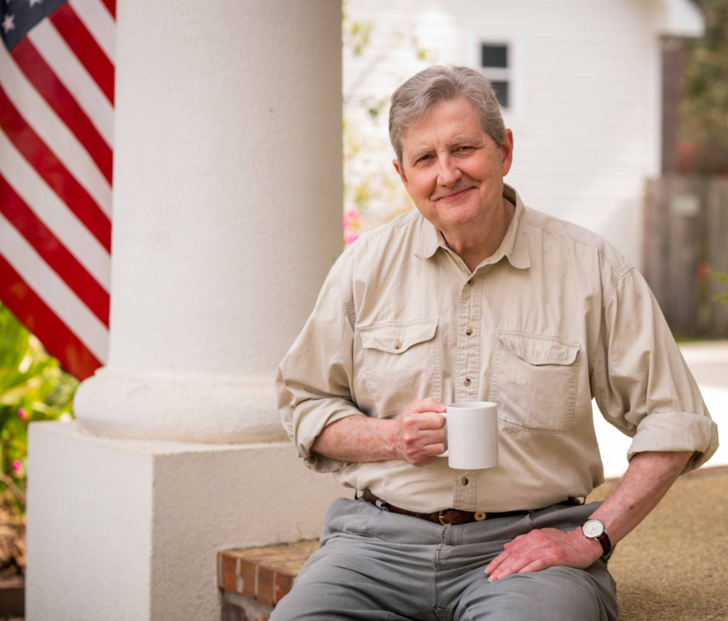 John Kennedy holding a coffee mug outdoors.